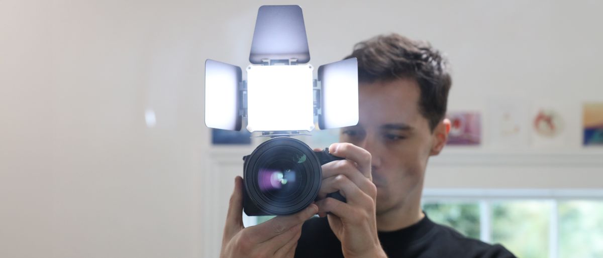 Zhiyun FIVERAY M20C LED panel mounted on a camera and held in front of a man&#039;s face