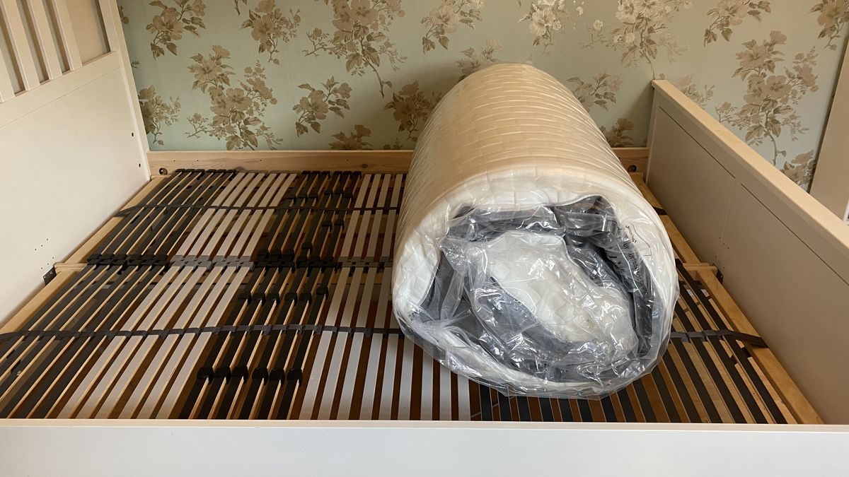 Levitex Gravity Defying Mattress review image shows the mattress being placed on a white wooden slatted bed base