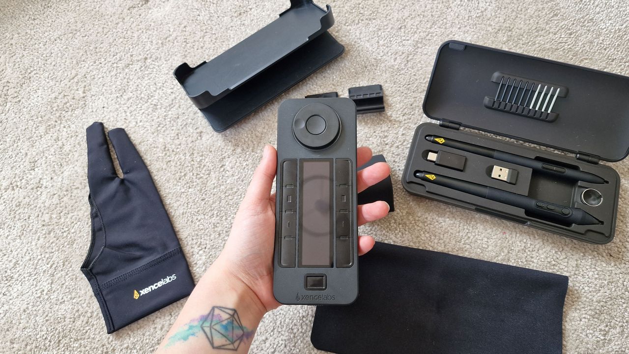 A photo of the Xencelabs Quick Keys being held above a collection of other tablet accessories