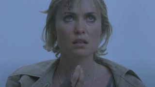 Radha Mitchell looks up in confusion while standing in a grey fog in Silent Hill.