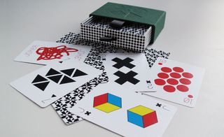 An open green box, with playing cards scattered around. The cards have symbols and patterns rather than the traditional designs