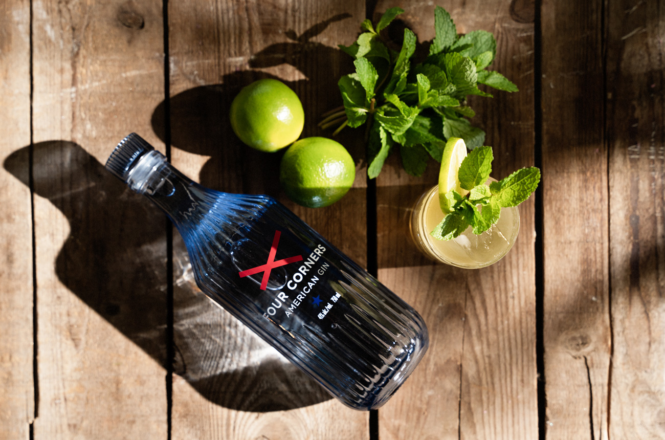 Bottle of gin, limes and a glass on wooden boards