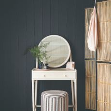 A vanity with a striped stool with a dividing bamboo screen next to it