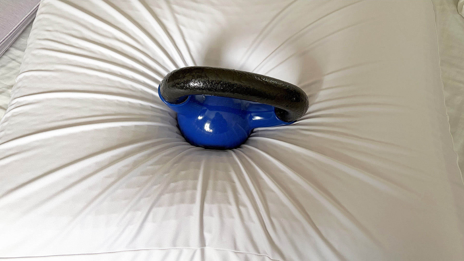 A weight resting in the middle of the Purple DreamLayer pillow