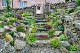 rustic stone steps leading up to a stone wall and gate