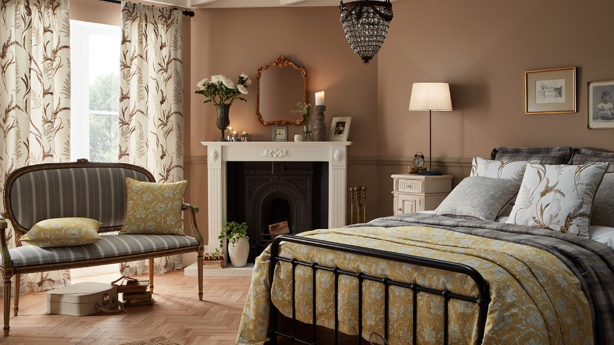 bedroom with white fireplace, peach walls, metal framed bed and small sofa