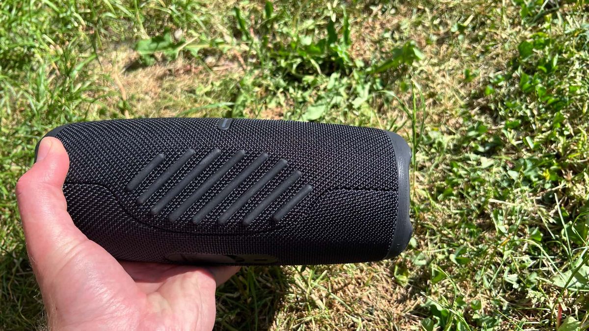 JBL Charge 5 Wifi med gr&auml;smatta i bakgrunden