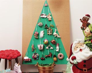 A pegboard painted in gold and green to depict a Christmas tree with baubles and Christmas decor