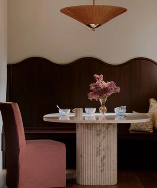 dining room with a white marble table, red chair, and dark wood wall feature