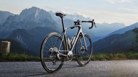 A Trek Domane on a road in front of some towering mountains 