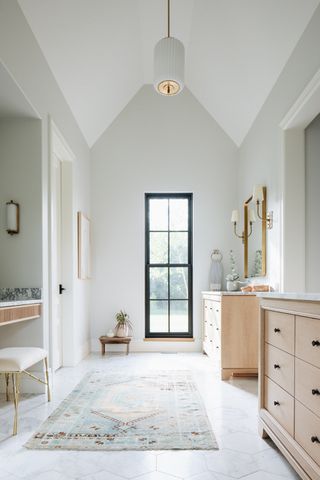 modern bathroom with pitched ceiling and double sinks with timber cabinetry and bathroom rug