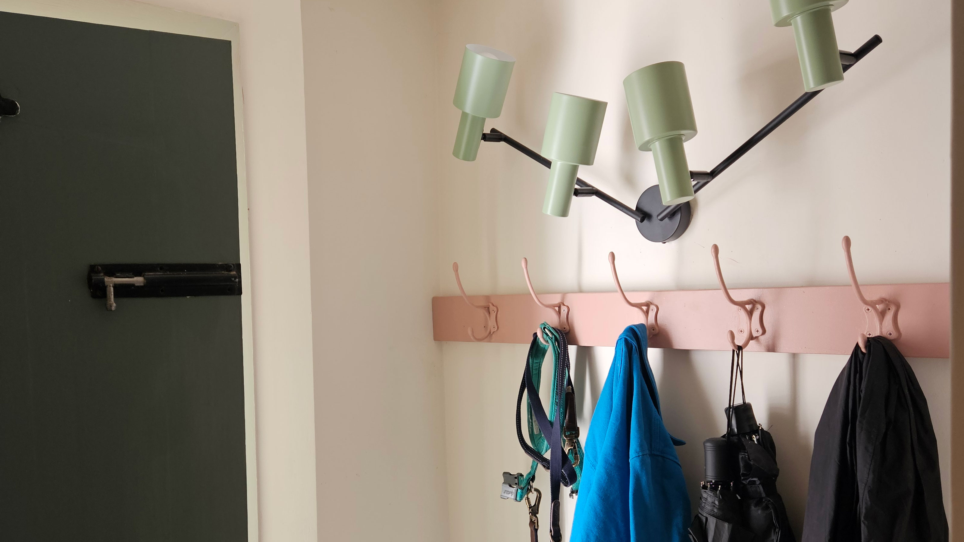 White porch with pink hooks and statement wall light