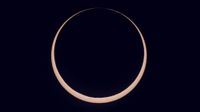 the sun is partially blocked by the moon during annular solar eclipse and appears as a glowing orange ring of light.
