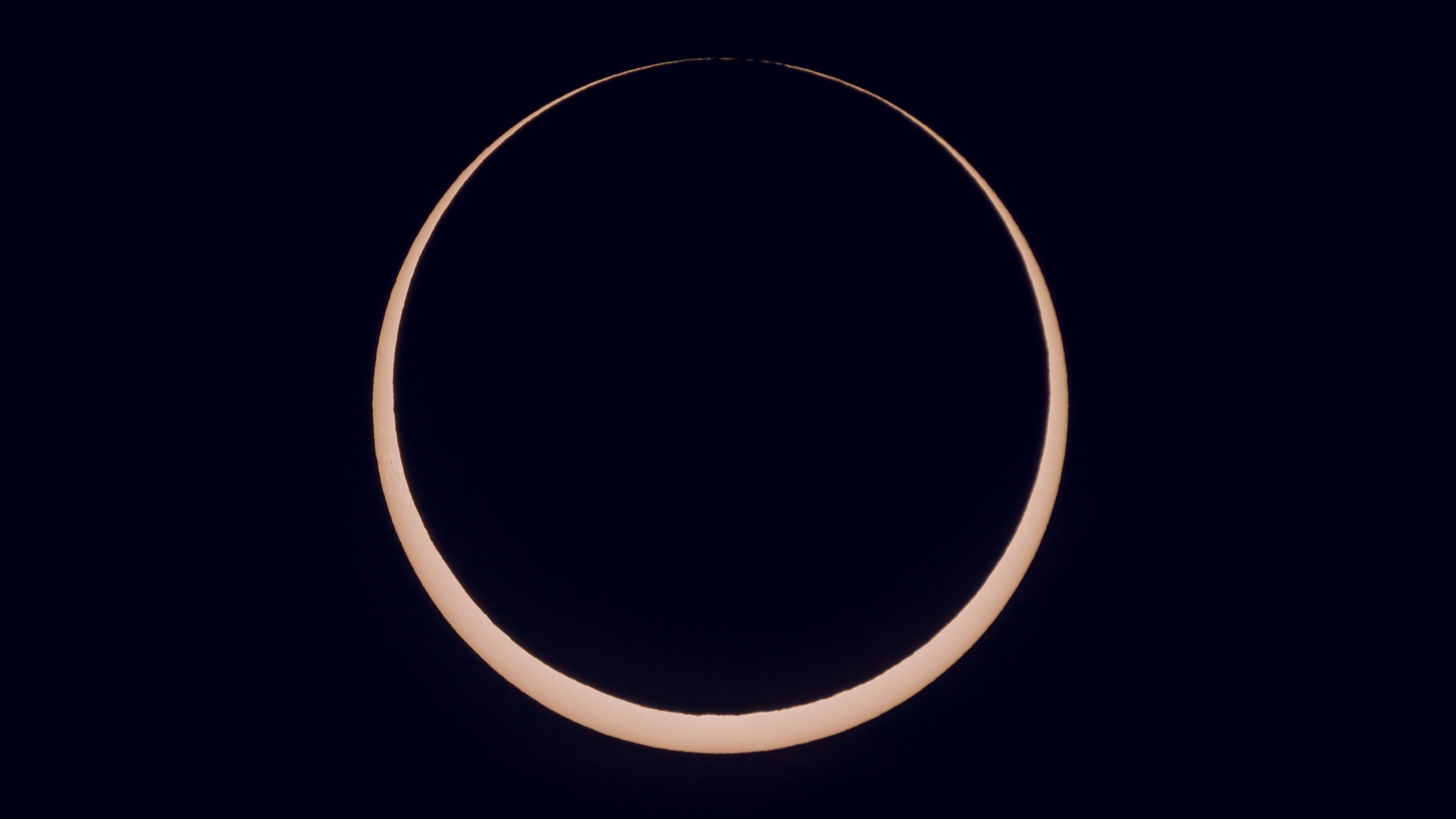 the sun is partially blocked by the moon during annular solar eclipse and appears as a glowing orange ring of light.
