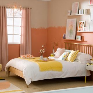 Pale orange bedroom, fitted shelves with framed abstract art, wood double bed position against wall