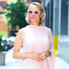 Pamela Anderson wears a light pink dress with white heeled shoes whilst promoting her new film, The Naked Gun