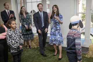 Prince William, Prince Harry, and Kate Middleton, who is wearing a blue floral dress, laugh while singing at the Charities Forum at BAFTA on October 26, 2015