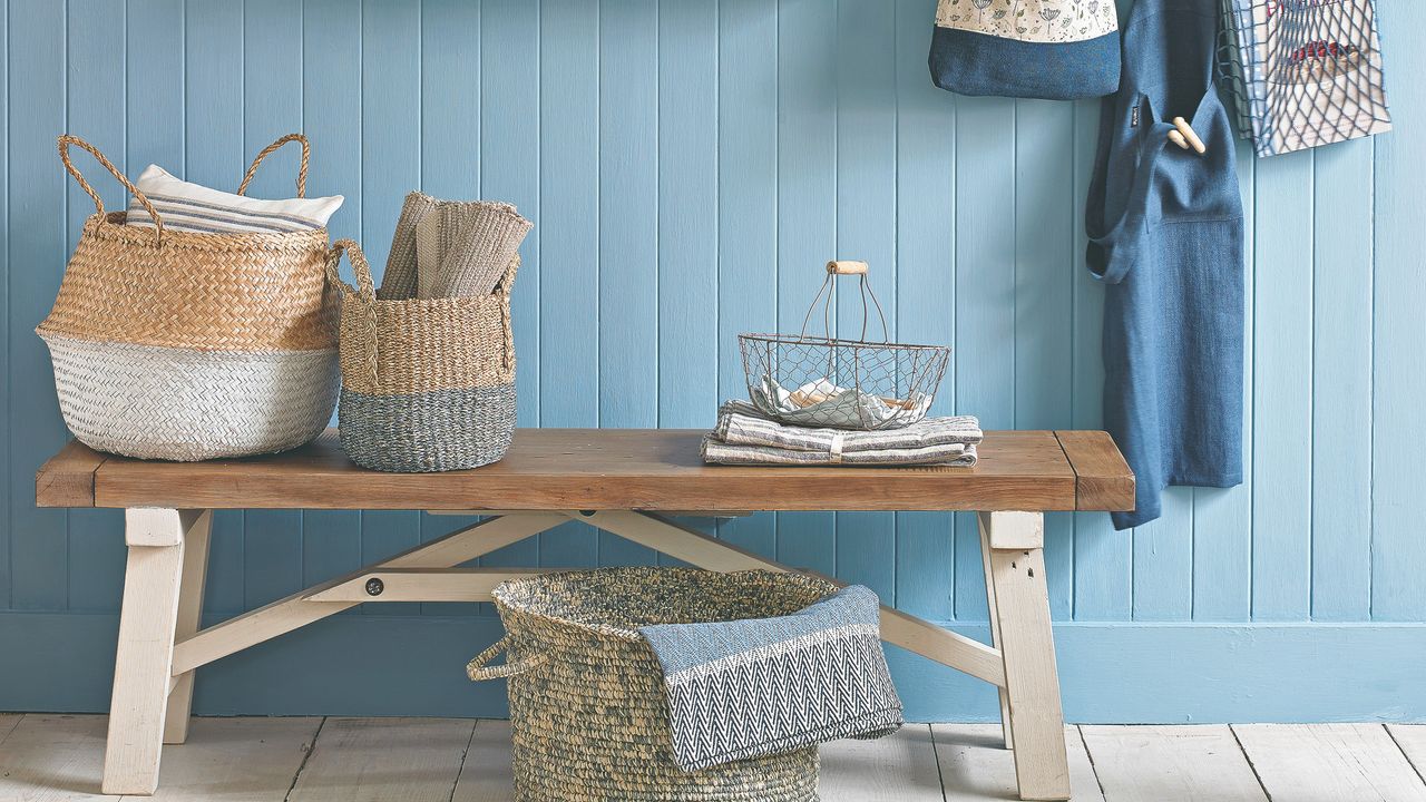 A hallway with a bench and wood wall panelling painted light blue