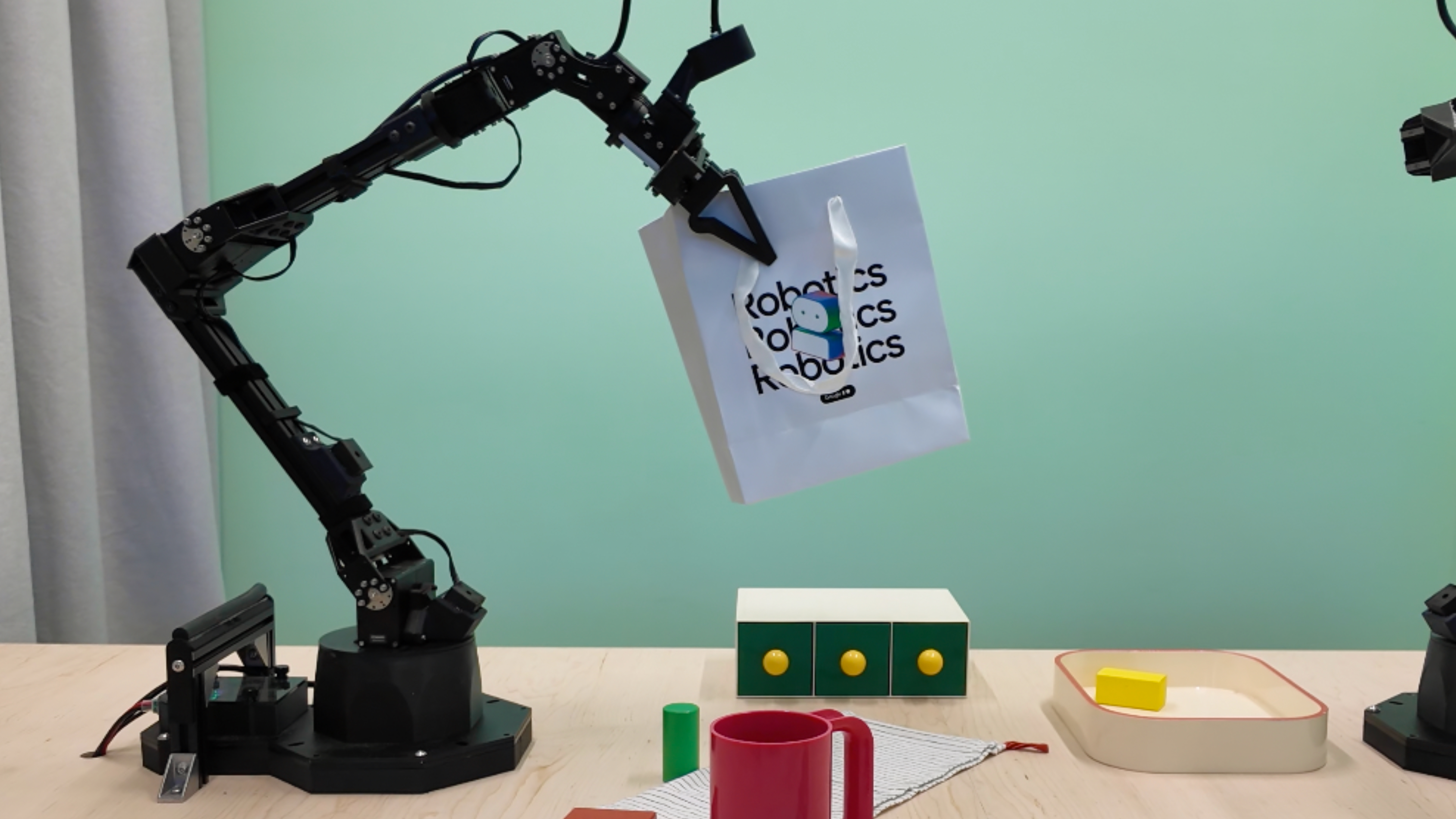 Gemini's robot arms picking up a gift bag.