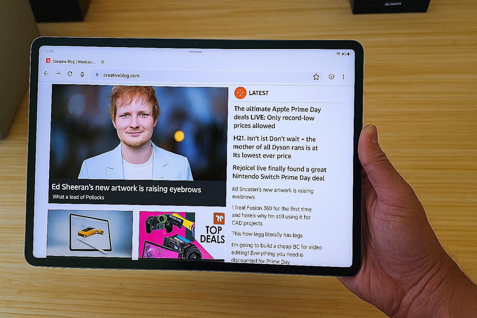 Hand holding tablet showing homepage of Creative Bloq featuring Ed Sheeran