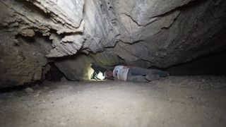 A caver slides through the salt cave under Mount Sedom.