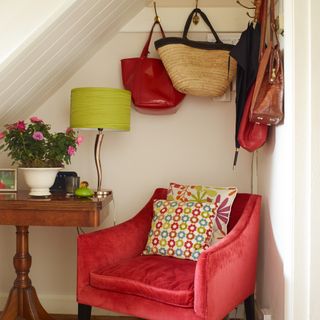 A reading nook under the stairs with a pink velvet chair