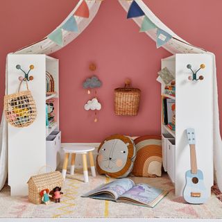 Nursery painted dark pink with two white IKEA shelving units used to create an activity area