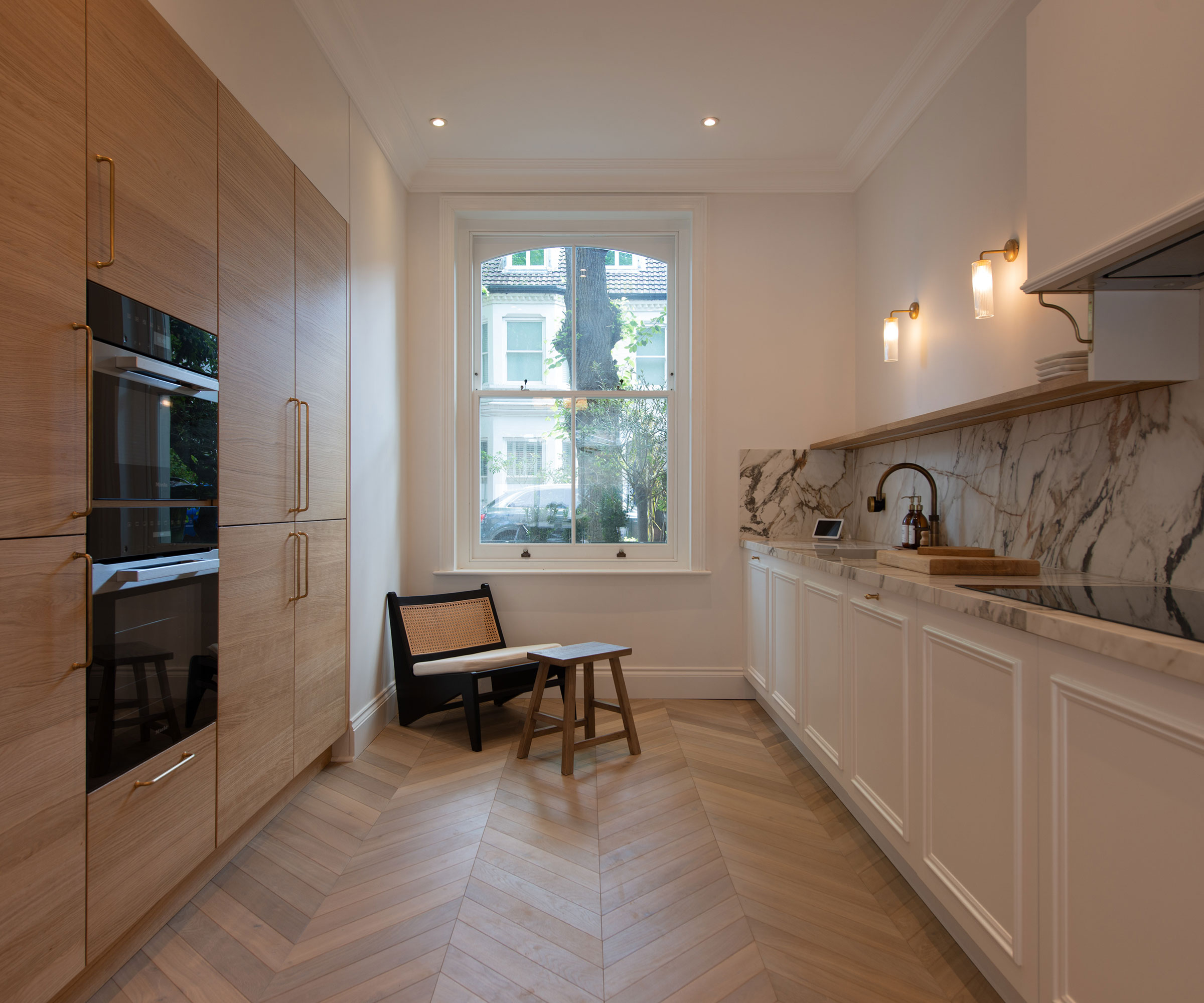 wooden galley kitchen with marble splashback and chevron wooden flooring