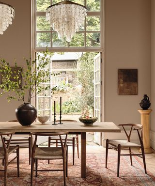 dining room with beige walls, wooden table and chairs, large double doors opening onto the garden