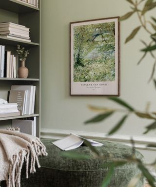 A green living area with a bookcase and wall art