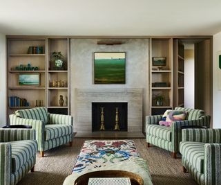 living room with patterned ottoman and green striped chairs and fireplace