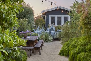 lushly planted backyard with gravel path and string lighting