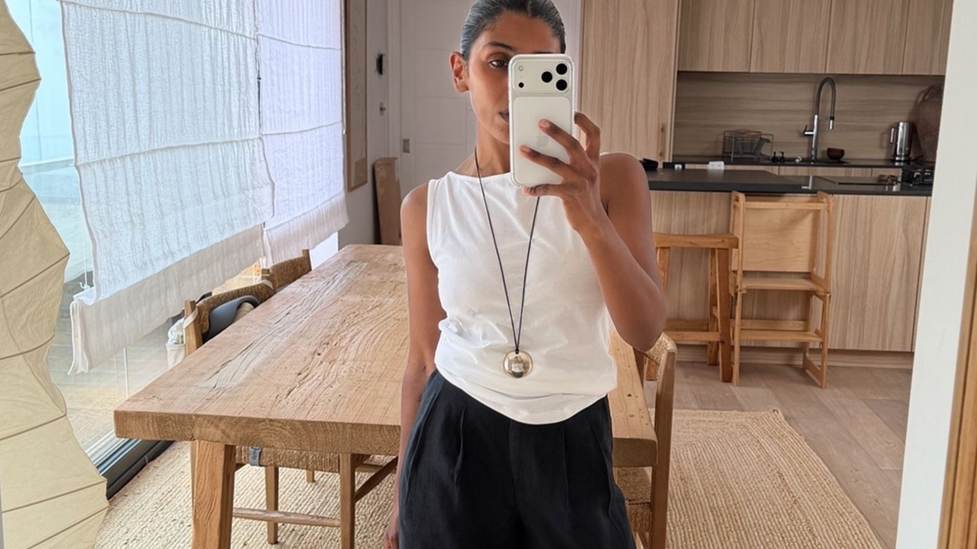Woman wears white top, black linen balloon trousers 