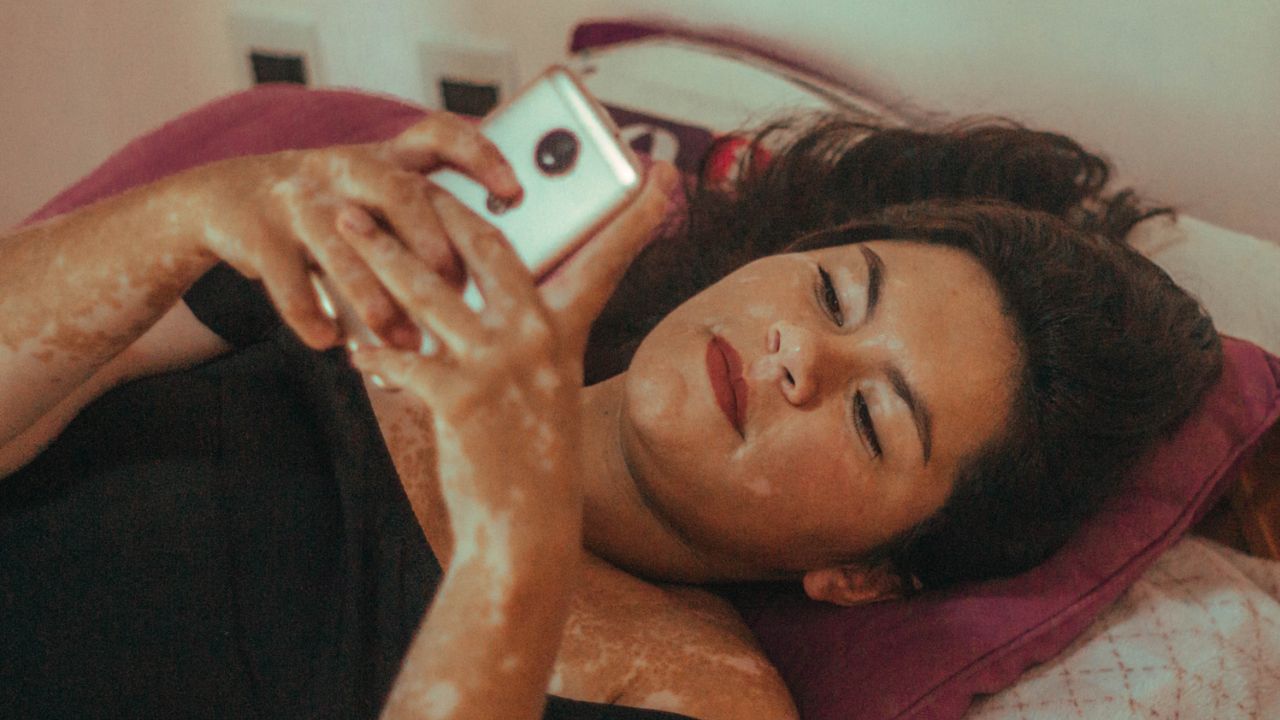 Woman using her phone in bed - stock photo