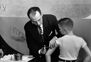 Dr. Jonas Salk inoculating a young boy with his new polio vaccine.