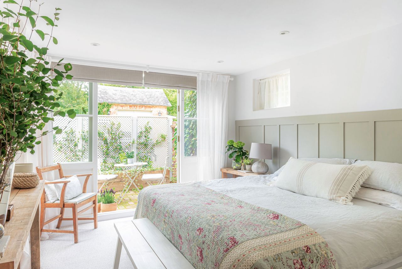 bedroom with french doors open to courtyard and pattened bed throw plus panelled headboard