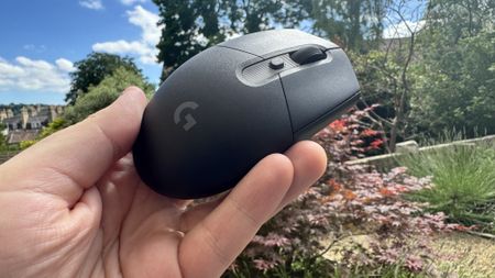 Logitech G305 X Superlight gaming mouse, held in a hand outside