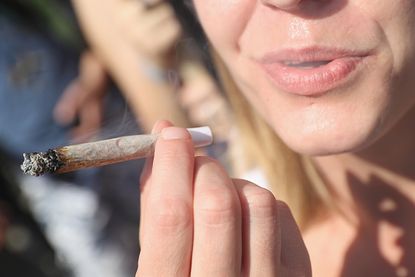 A woman smokes a marijuana joint.