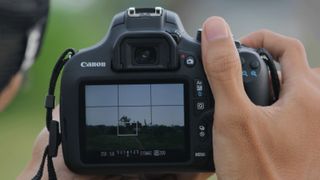 Two hands holding up a DSLR camera