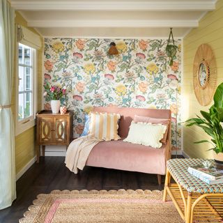 Summerhouse interior with floral wallpaper and pink sofa