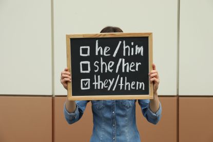 a chalkboard with a list of gender pronouns. 