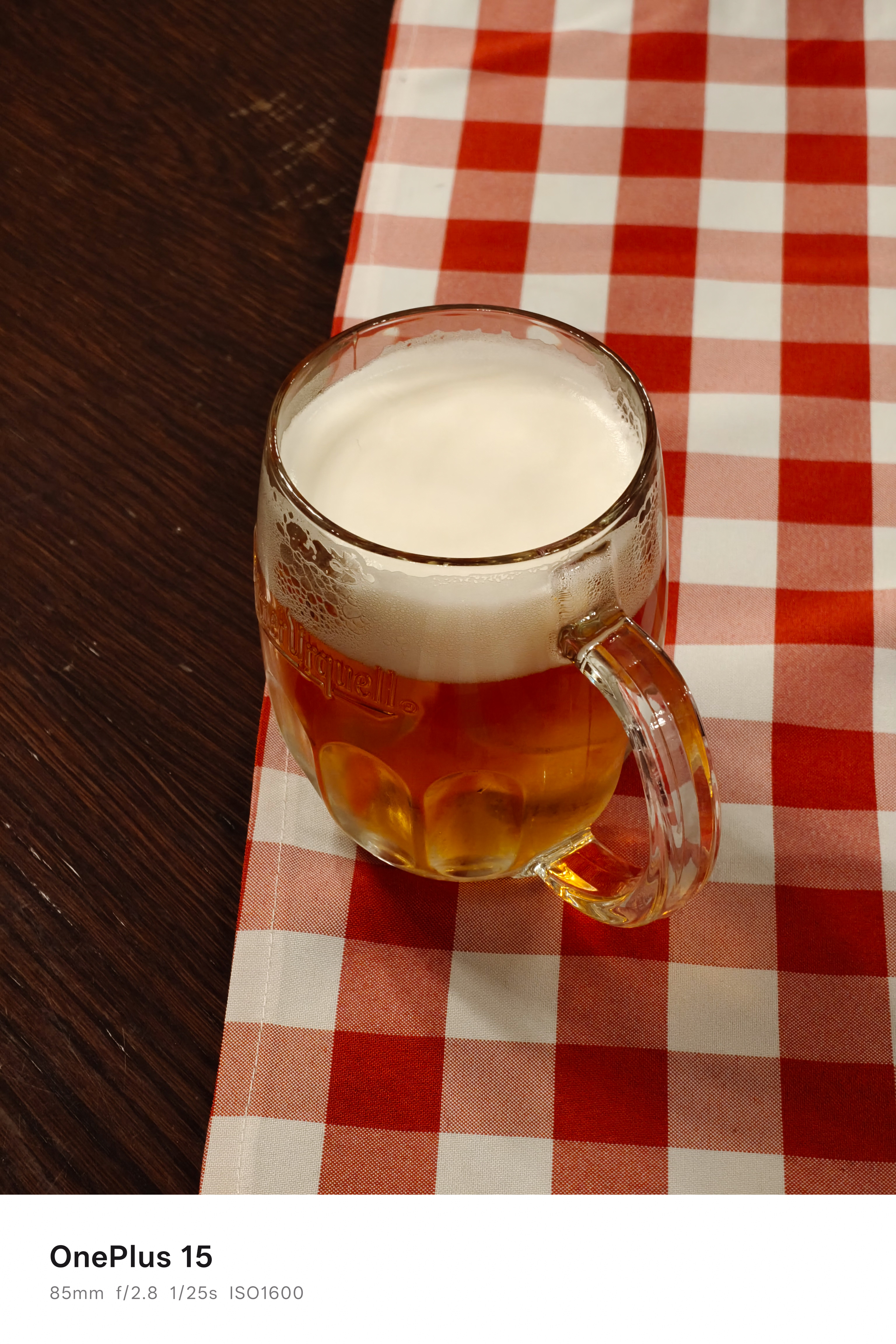 A pint of beer on a wooden table and chequered tablecloth