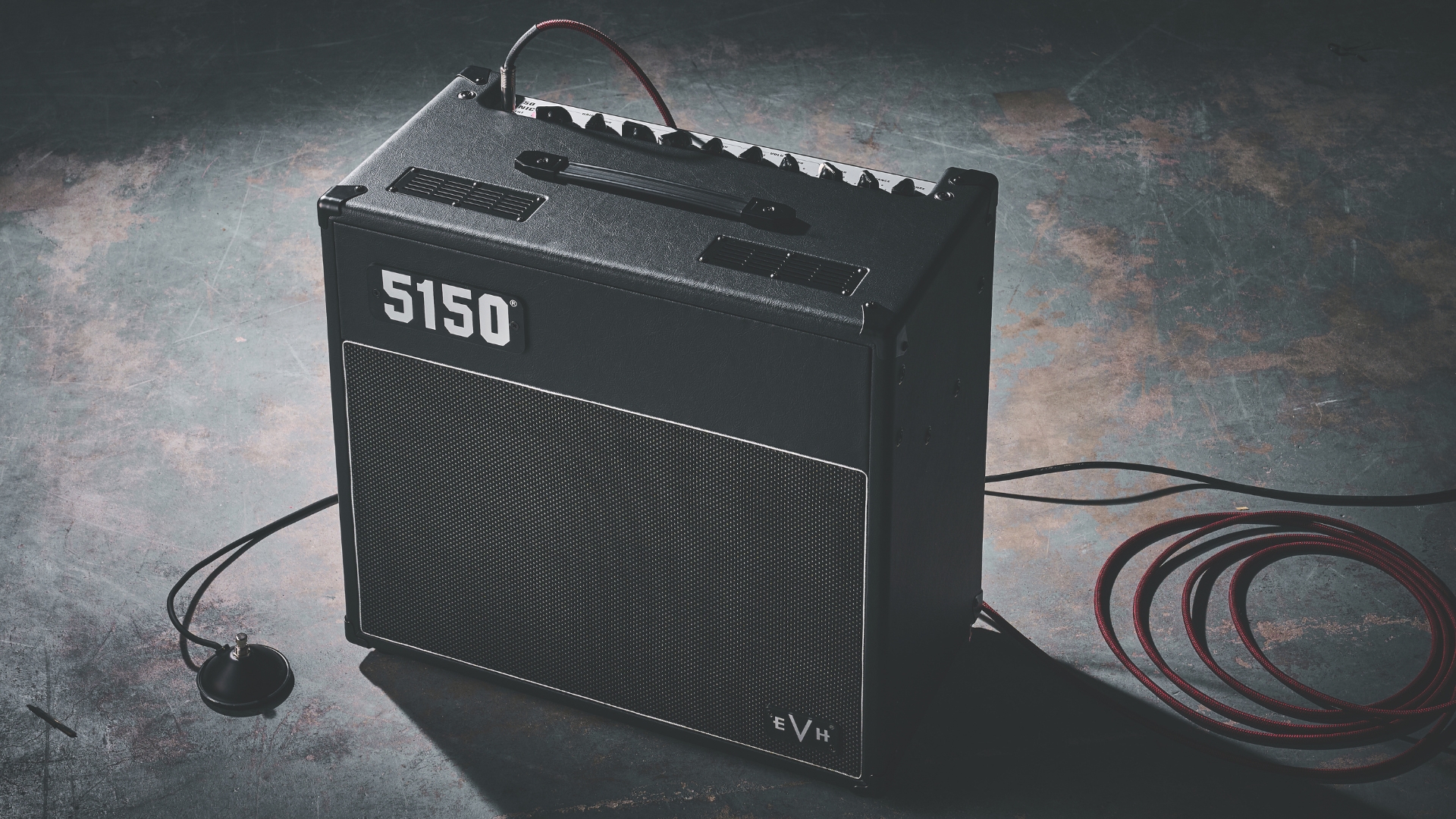 An EVH 5150 Iconic Series combo amp on a stone floor with a guitar cable and channel switcher