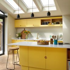 a modern yellow kitchen with white worktop and matching kitchen island