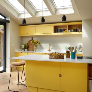 a modern yellow kitchen with white worktop and matching kitchen island