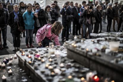 A child lights a candle in front of a makeshift memorial in Paris.