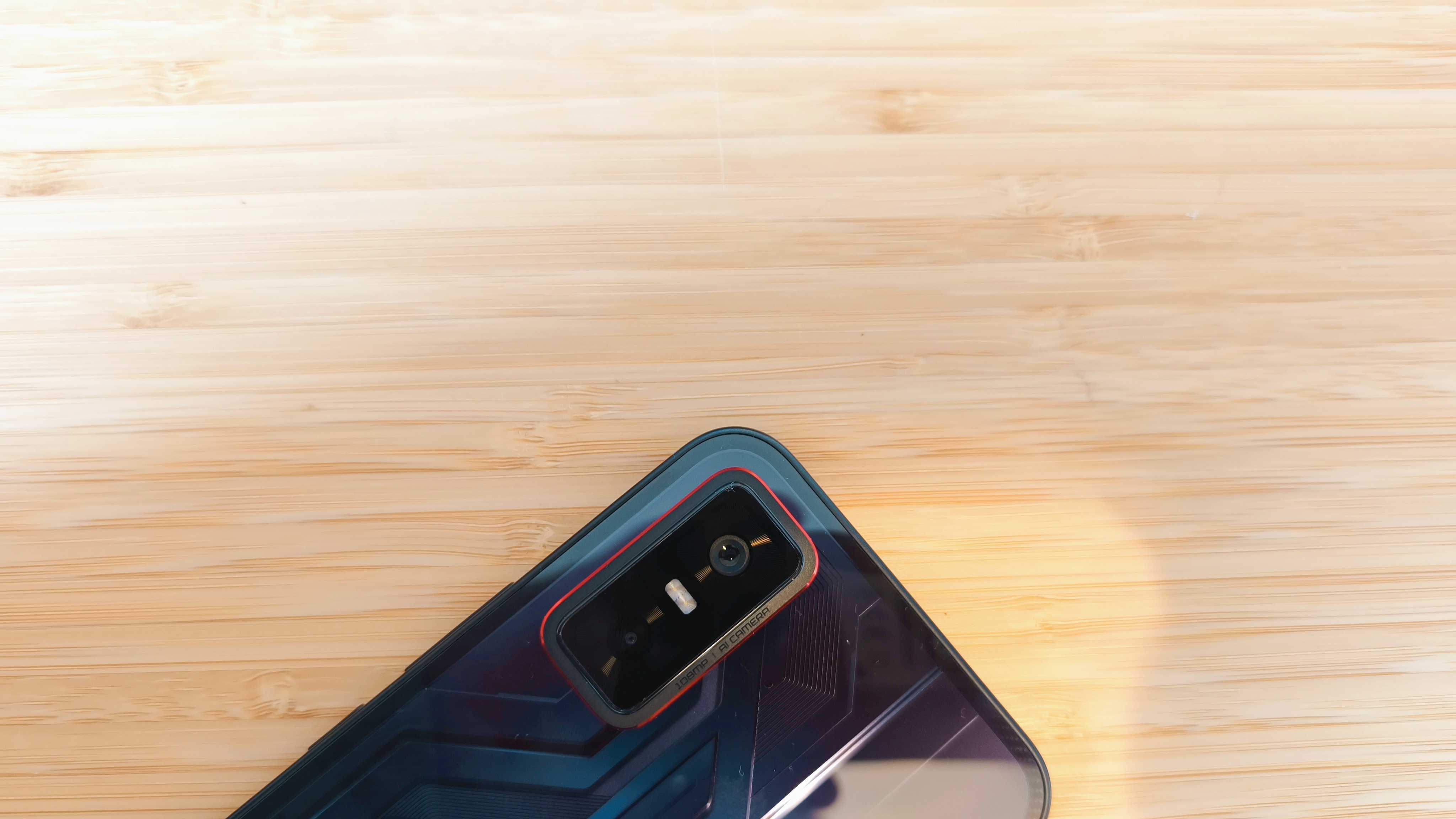 A black Infinix GT 30 Pro phone on a wooden desk