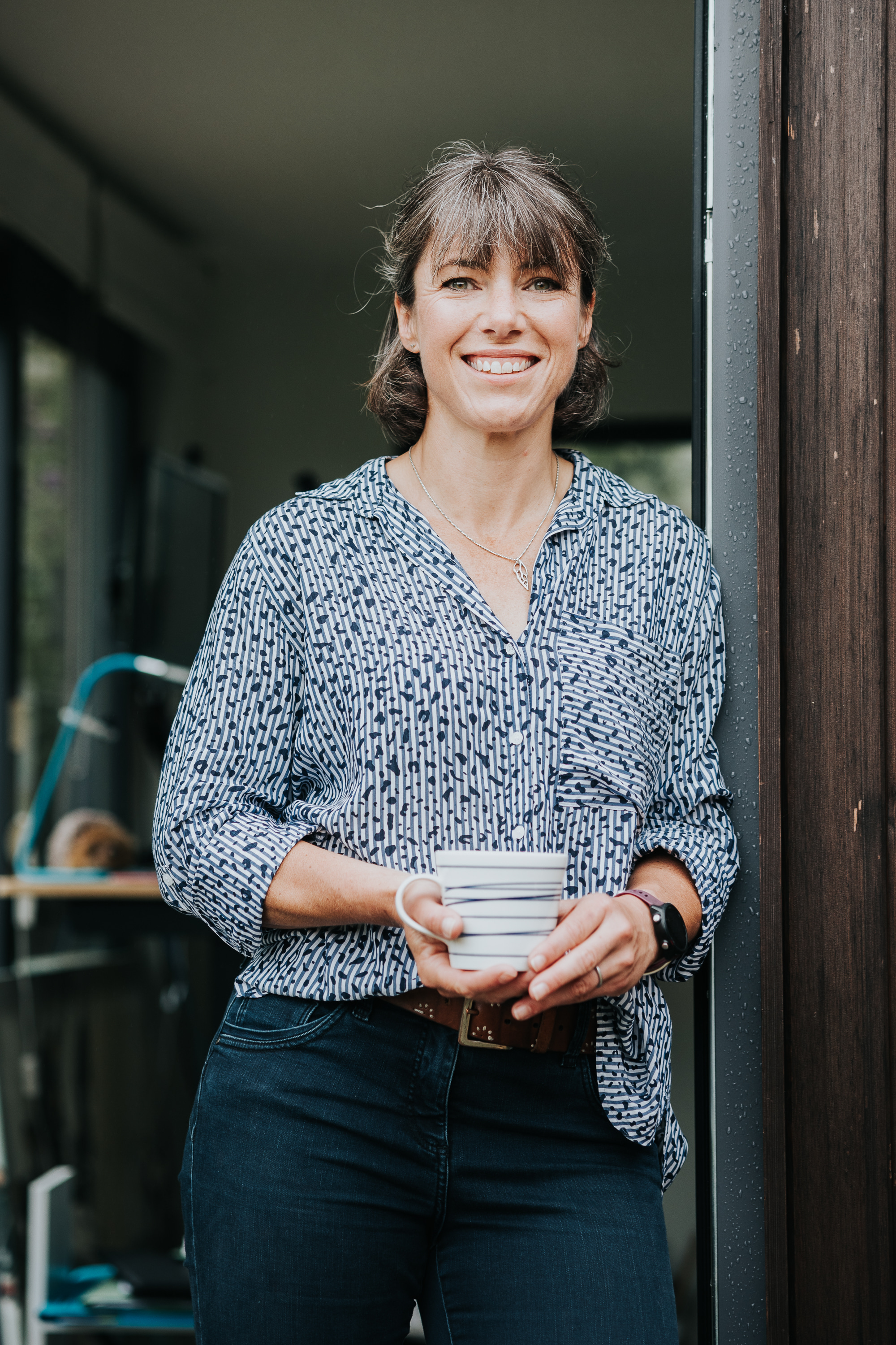 woman holds cup of tea standing smiling to camera