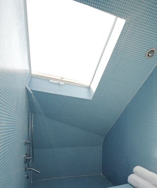 bathroom with blue tiles all the way up and skylight