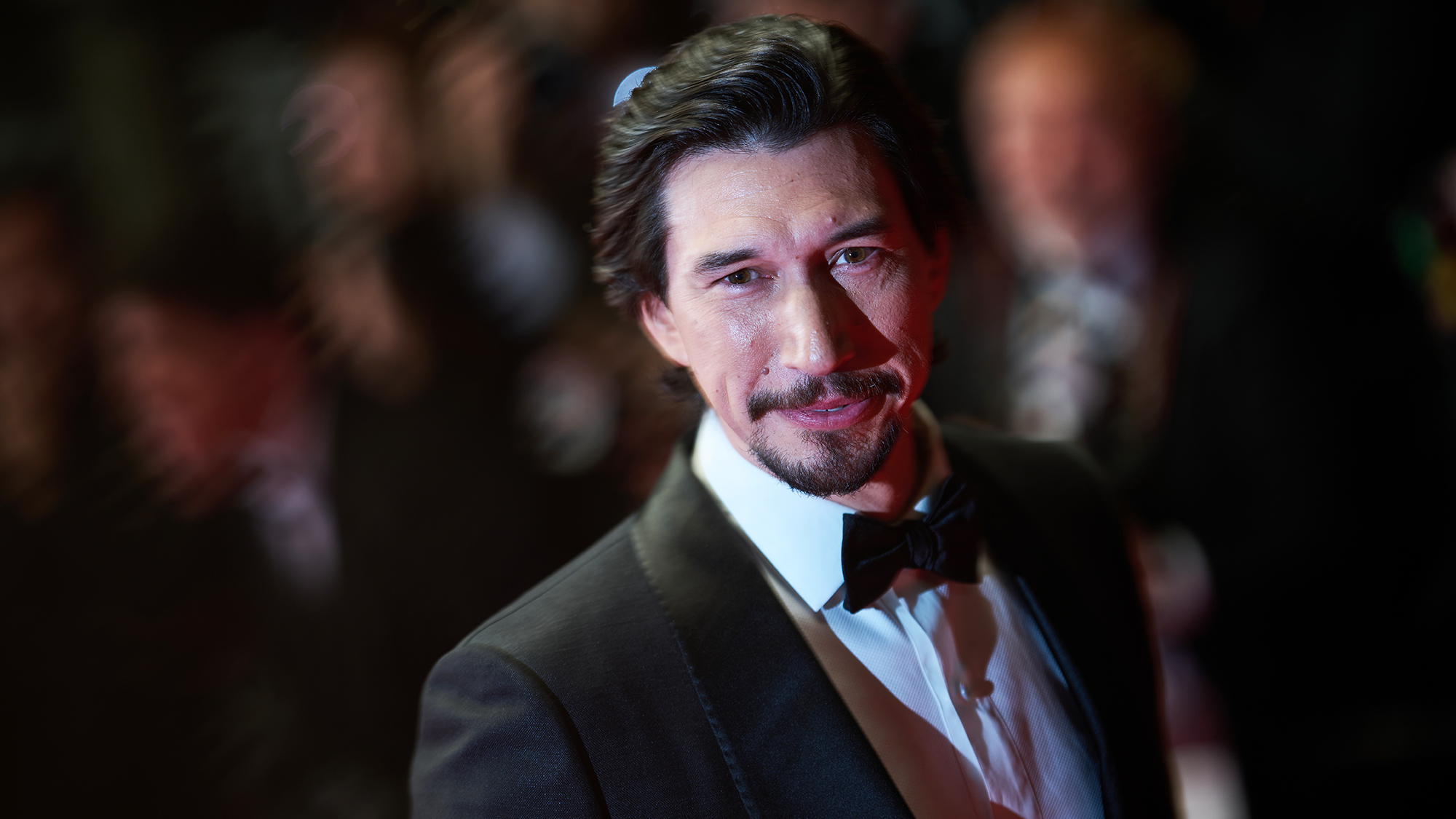 Adam Driver smiling while wearing a tuxedo during an event